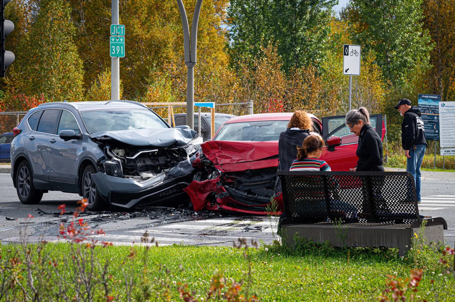 two cars that have been in a head on collision. bystanders or those involved in the accident surround the scene.