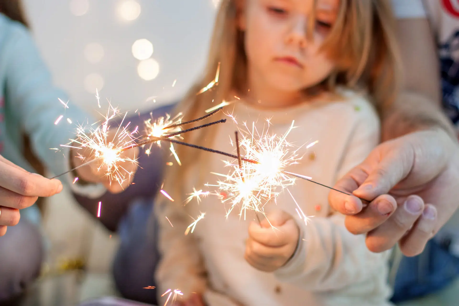 a child and her family hold sparklers to celebrate a holiday