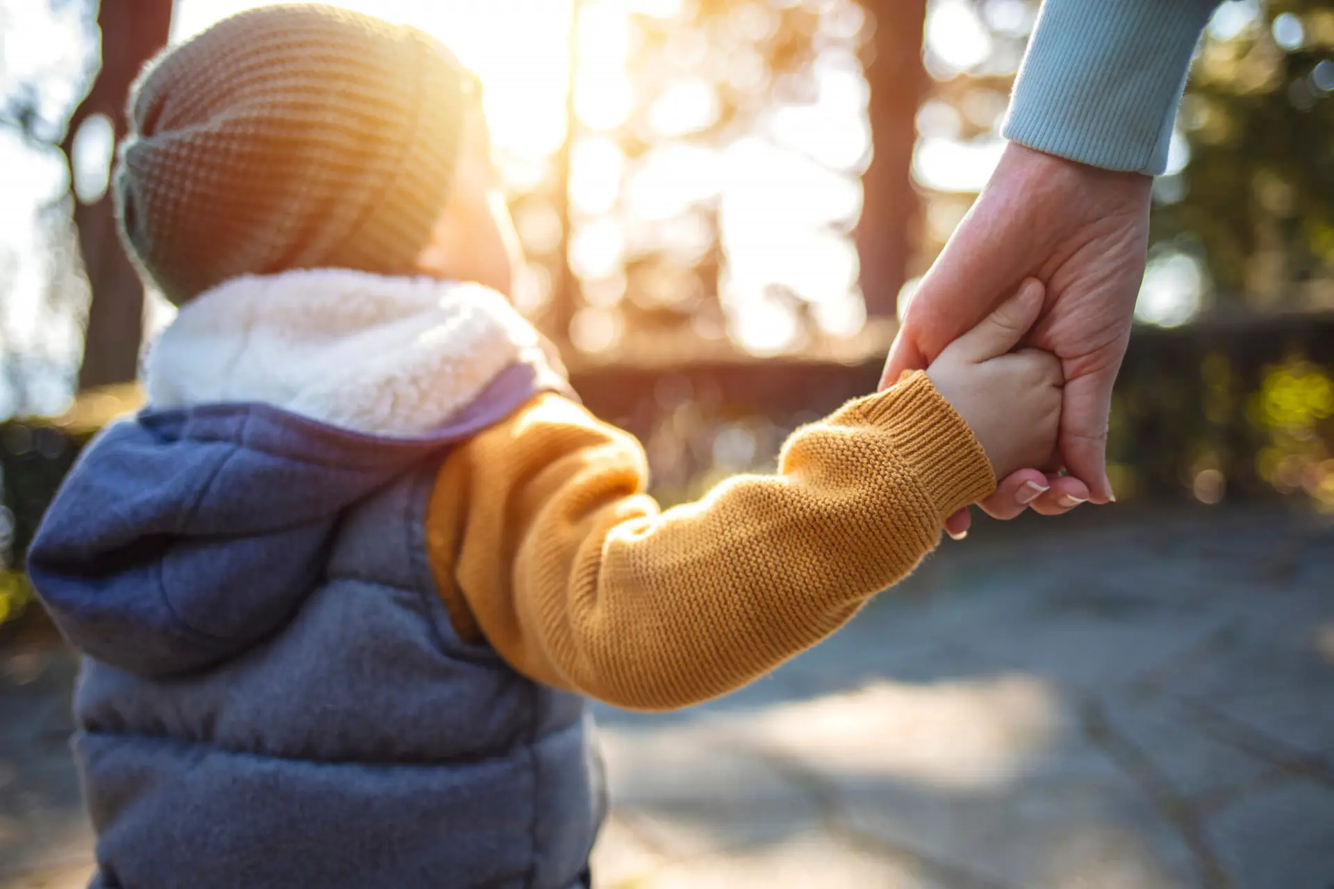 a child who may have been in the care of children aid society holds hands with an adult