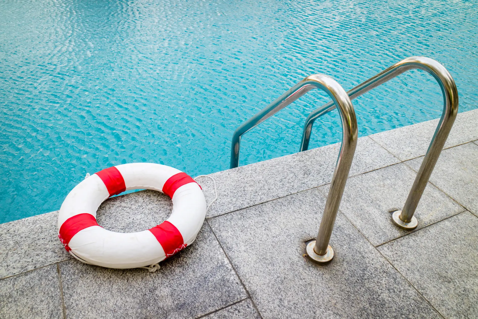 a swimming pool is equipped for use with a life preserver on the sidelines