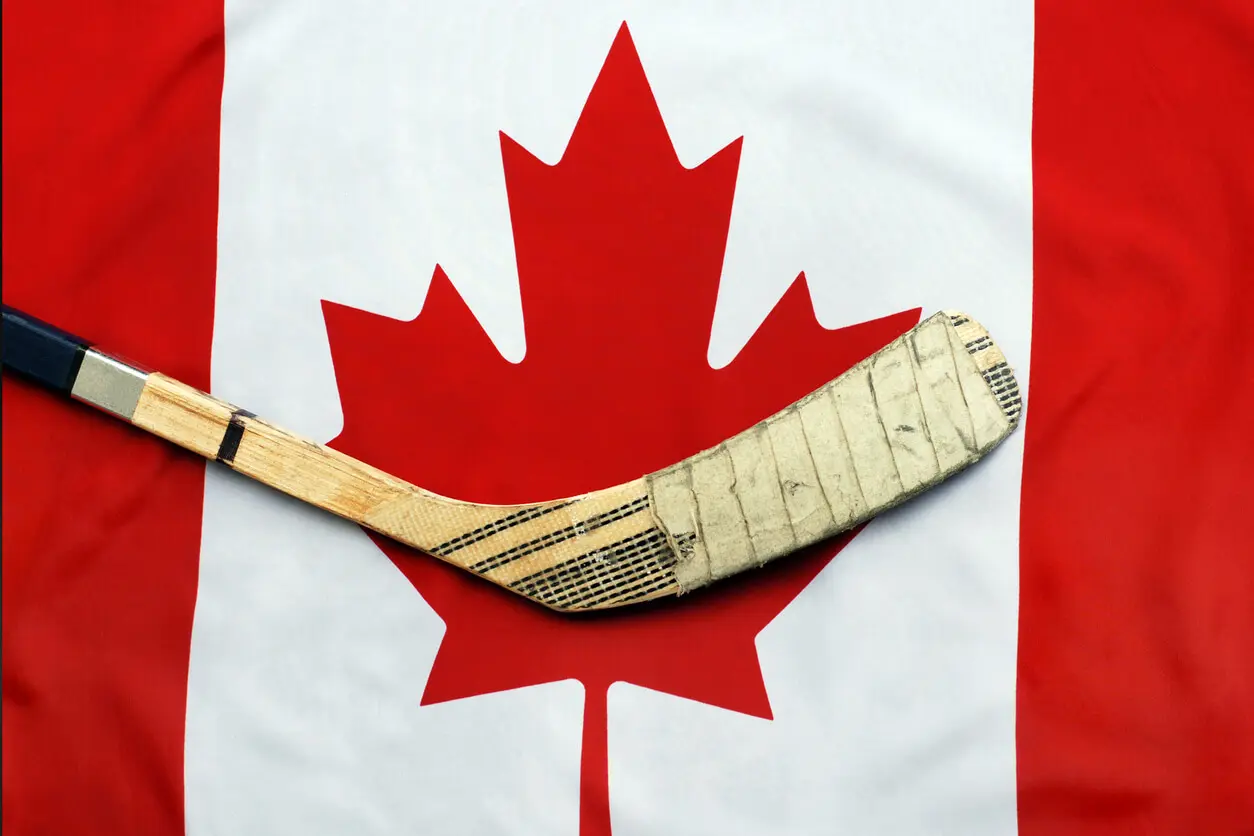 a hockey stick rests on top of the Canadian flag