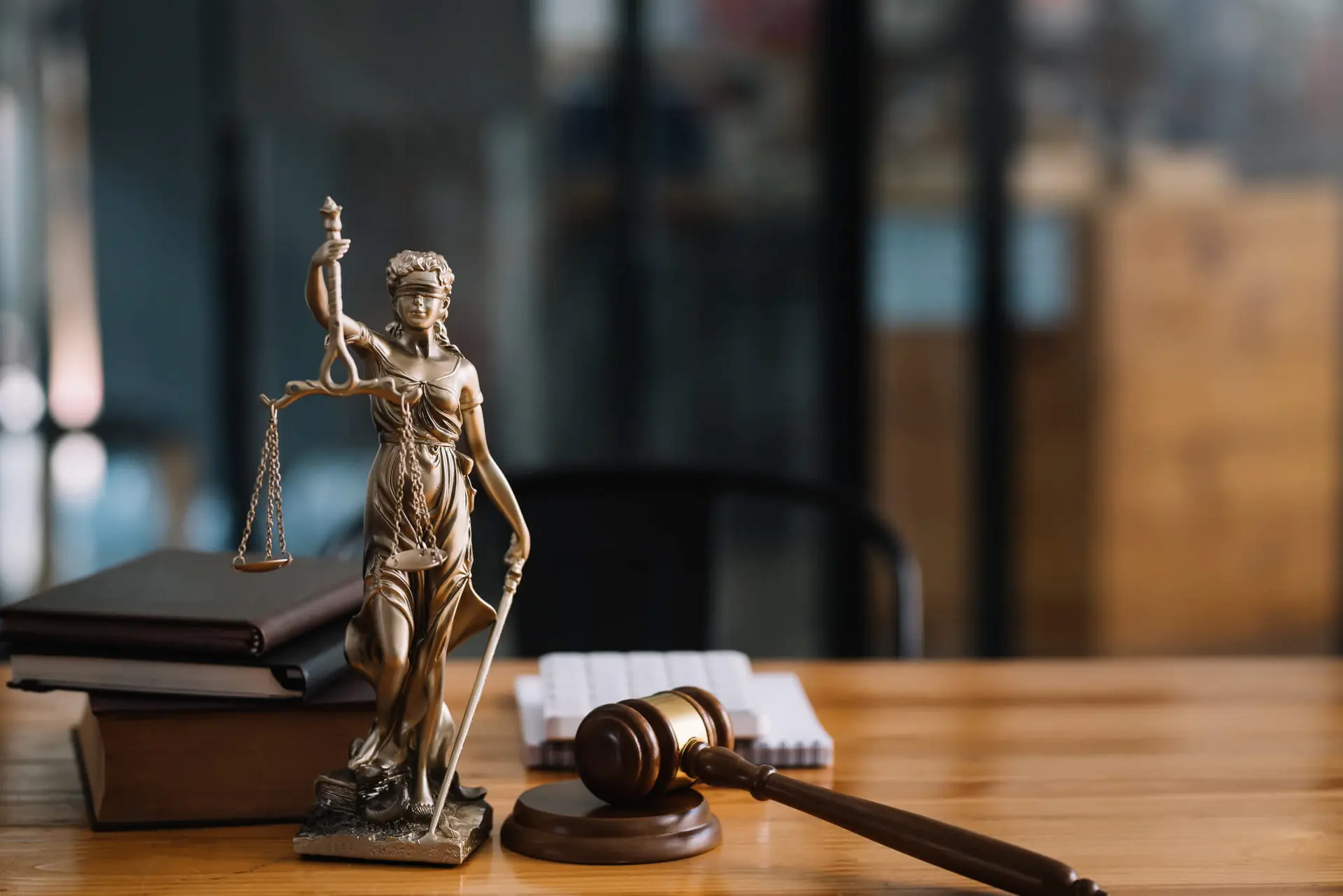 a figurine of lady justice next to a gavel on a judge's desk