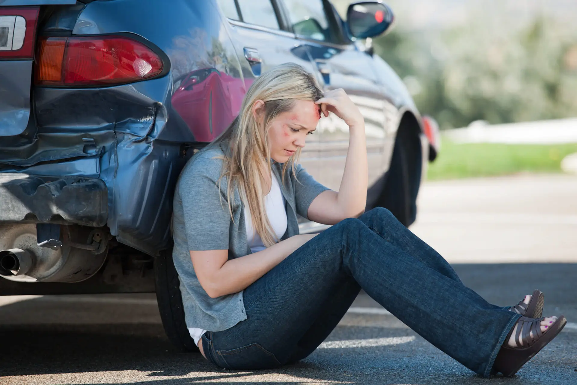 a woman who just got into a motor vehicle accident and is potentially injured sits and thinks about what to do next